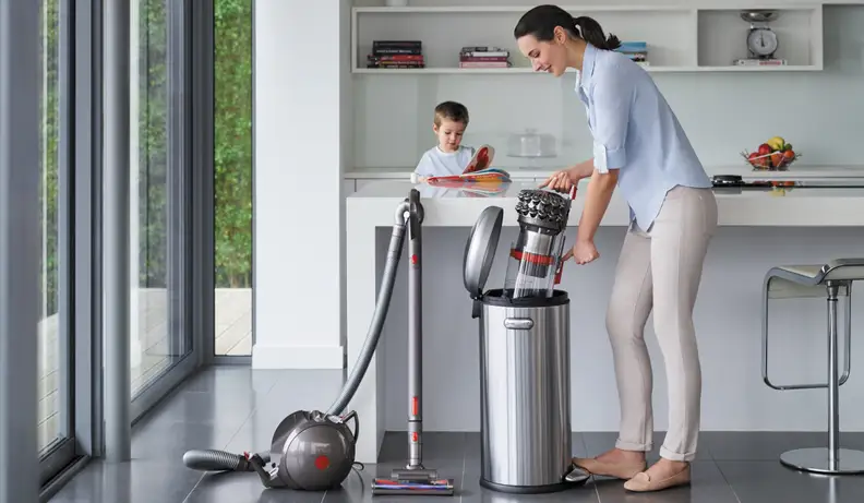 A woman emptying a Dyson vacuum into the trash