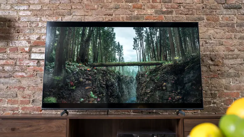 The TV sits on a table, showing a scene of a cloudy forest