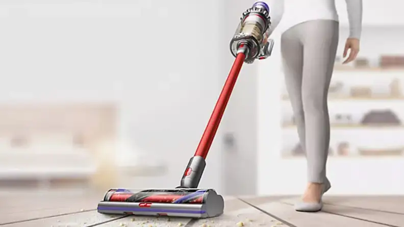 A person vacuums a home floor with a Dyson vacuum.