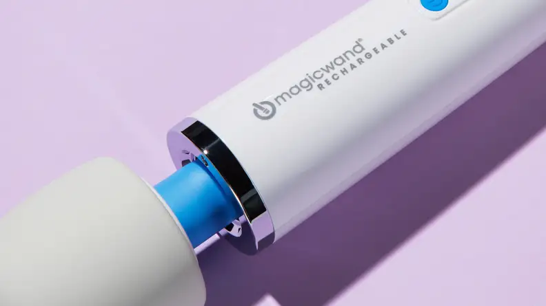 Close-up photo of the Magic Wand Rechargeable resting on a lilac surface. The focus of the photo is the neck joint where the vibrator head meets the main body.