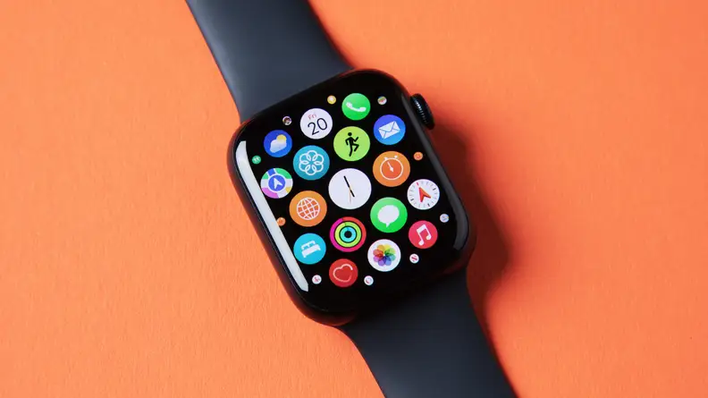 An Apple Watch Series 8 with its app interface open, sits on an orange background.