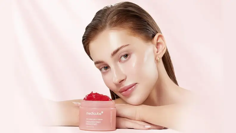Pink Medicube Collagen Jelly Cream container in front of young woman, against a light pink background.