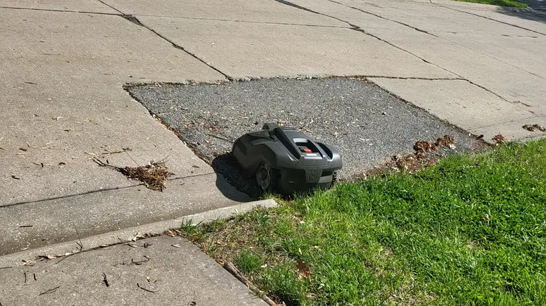Automower parked in the street just beyond the yard