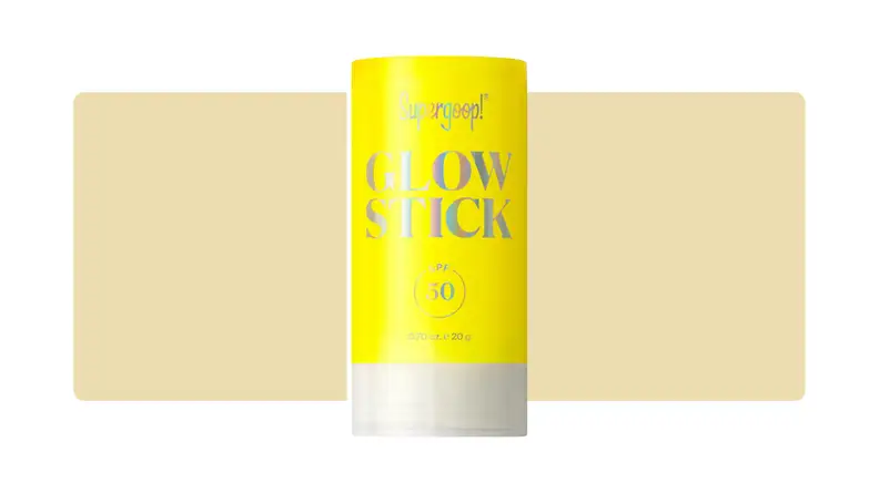 Supergoop sunscreen stick in front of a yellow background.