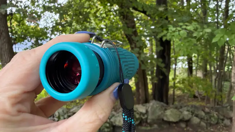 a hand holding an aqua blue monocular