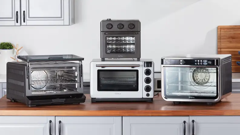 Four countertop ovens, partially stacked, on a kitchen counter