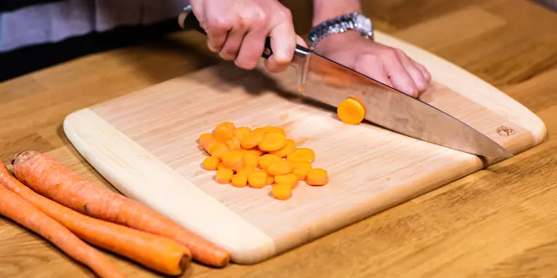 Cutting board with a knife cutting carrots