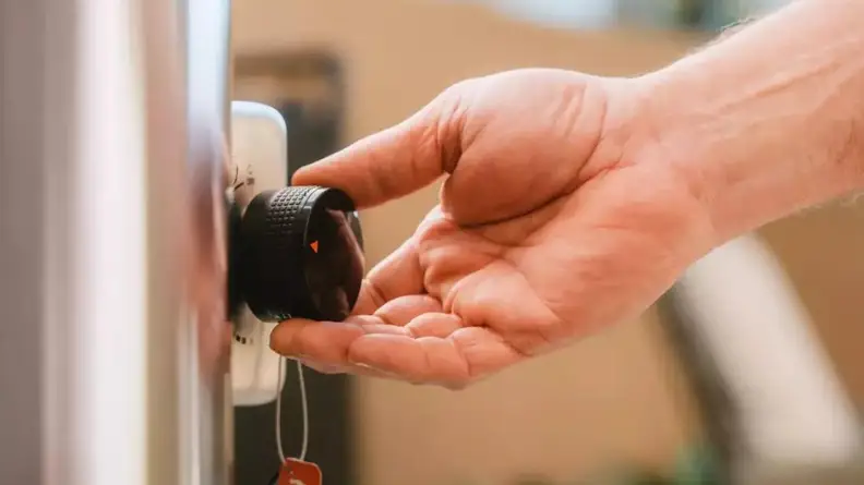 Person adjusting the temperature dial on side of the Solo Pi Prime pizza oven.