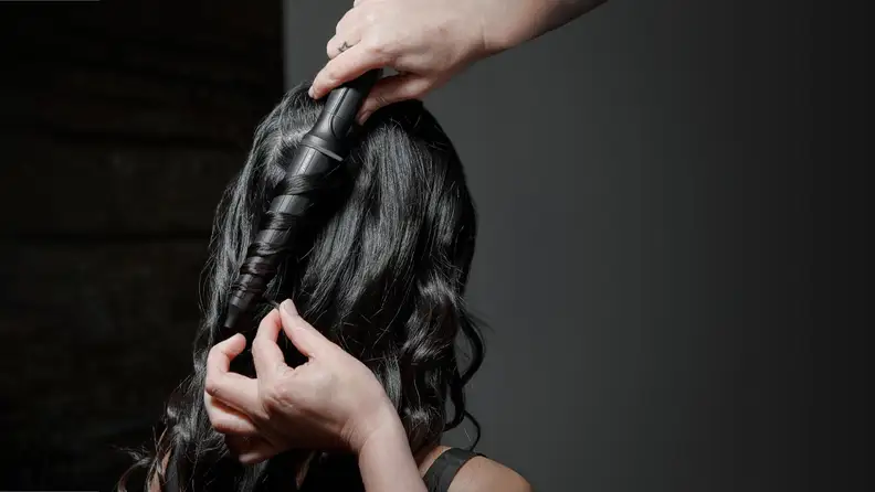 Stylist uses GHD Curve Creative Curl Wand on woman with long black hair