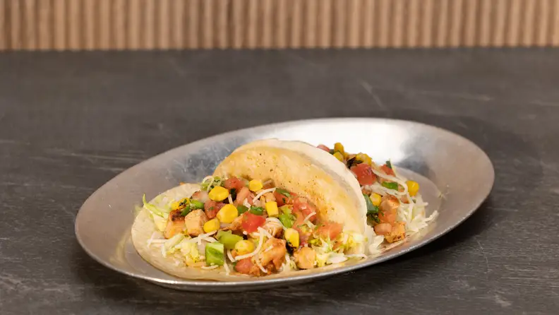 A chicken taco on a silver plate