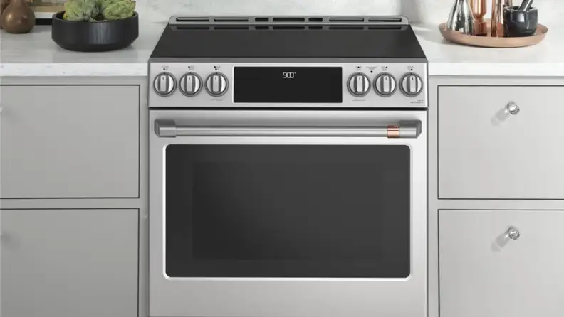 Cafe induction range with rose gold hardware surrounded by kitchen cabinets