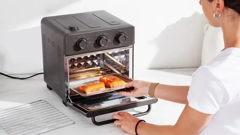 A person taking food out of the Our Place Wonder Oven.