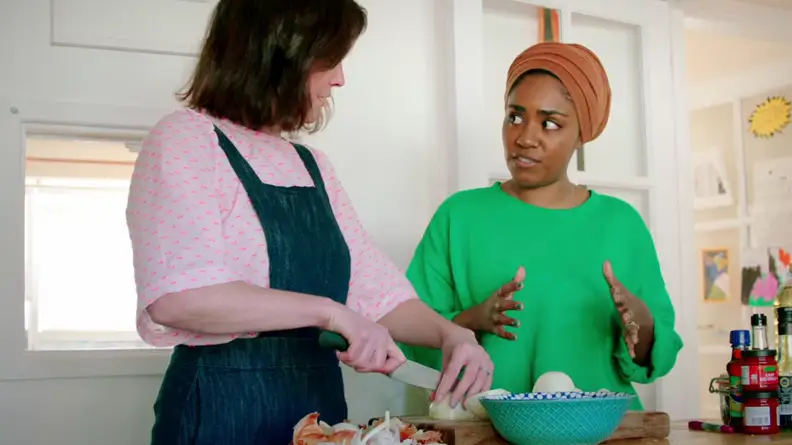 A still of Nadiya Hussain standing in her kitchen instructing on kitchen tips.