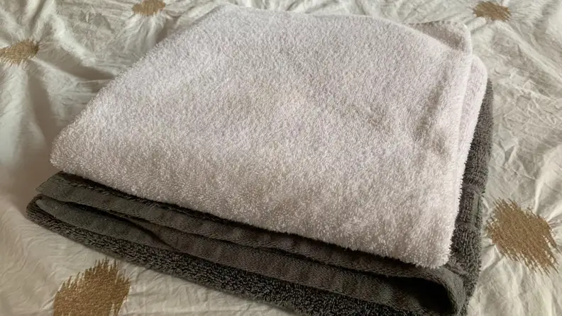 One light and one dark towel folded neatly on top of each other after cleaning