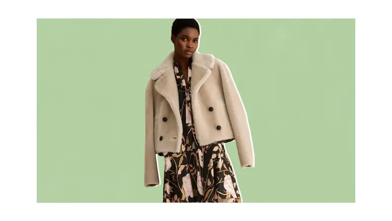 A model wearing a cropped shearling double-breasted jacket with a floral dress.