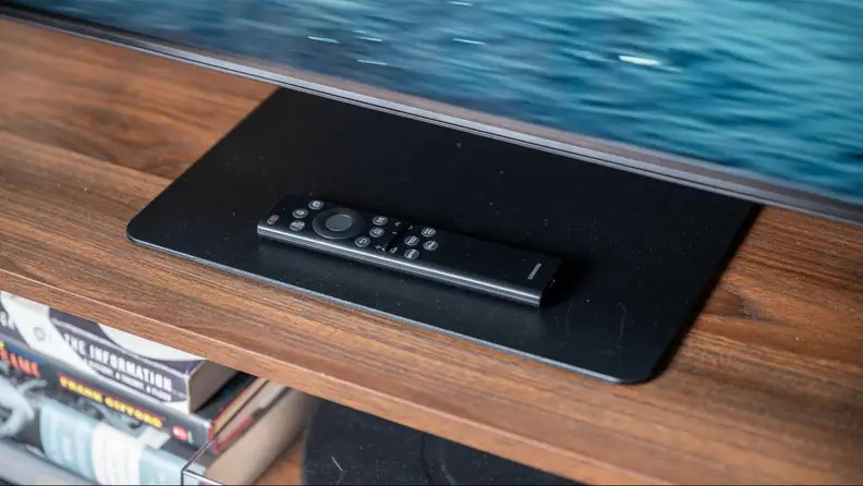 The TV stand of the Samsung QN90B with a remote on top.