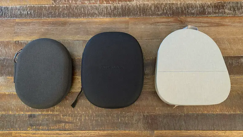 The cases for the Sony WH-1000XM4, B&W Px7 S2, and Sony WH-1000XM5 next to one another on a wooden table.