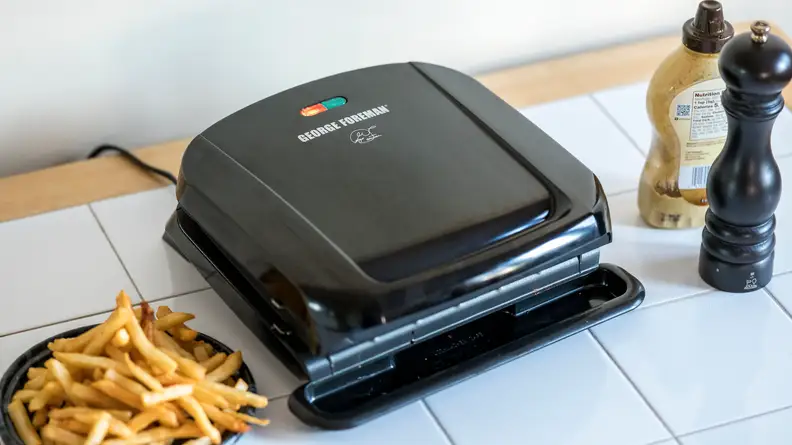 A black George Foreman 4-Serving Removable Plate Grill viewed from a front right angle.