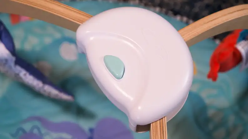 A close-up of a baby blue button, that helps set-up the Melissa & Doug Ocean Easy-Fold Play Gym.
