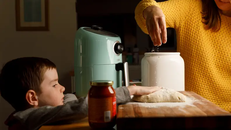 Parent and child making pizza.