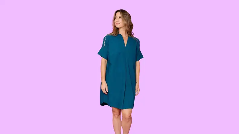 A woman modeling a dress in front of a background.