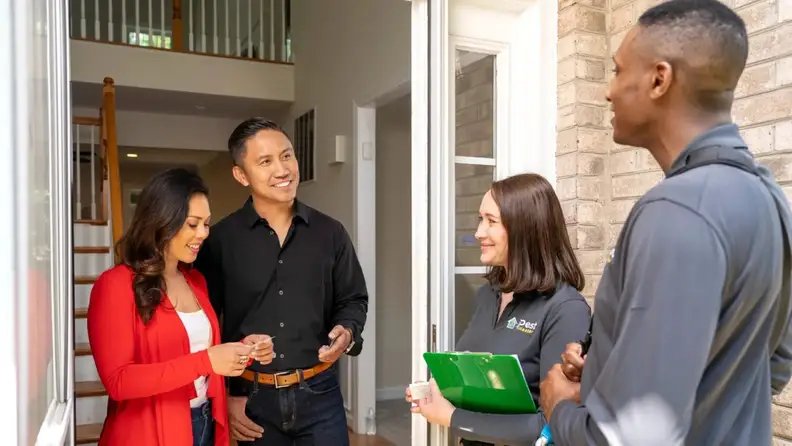 Two technicians speaking with homeowners at their front door