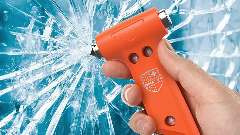 A person shatters a windshield with a safety hammer