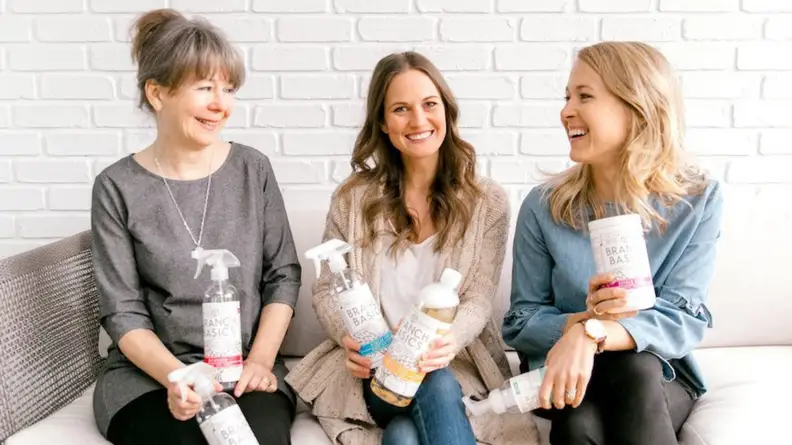 Three of the Branch Basics owners sitting down while holding their products.