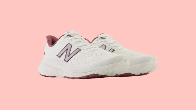 White sneakers with red details against a pink background.