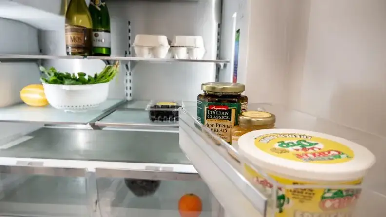 A close-up of an open Bosch fridge, showcasing its shelving and door bins.