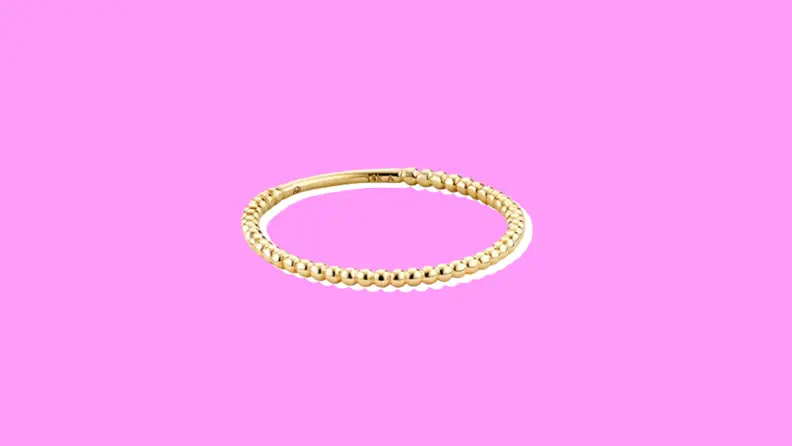 Mejuri Gold Beaded Ring on a purple background.