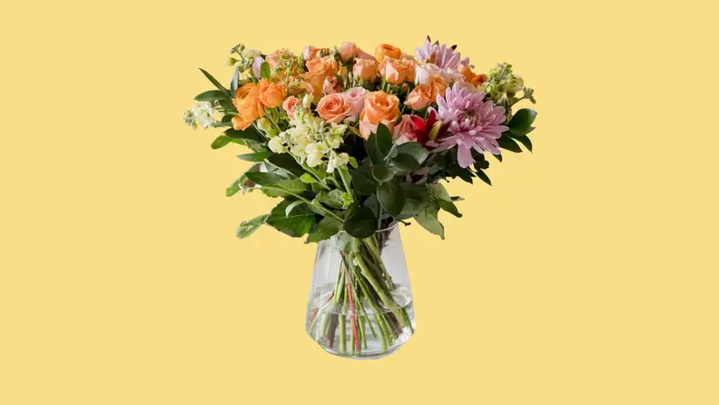 A bouquet of BloomsyBox flowers in a vase on a yellow background.