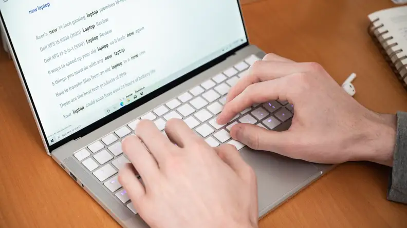 person types on a laptop's keyboard