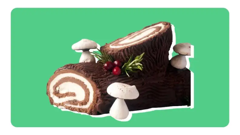 A French log-shaped Christmas cake in front of green background.
