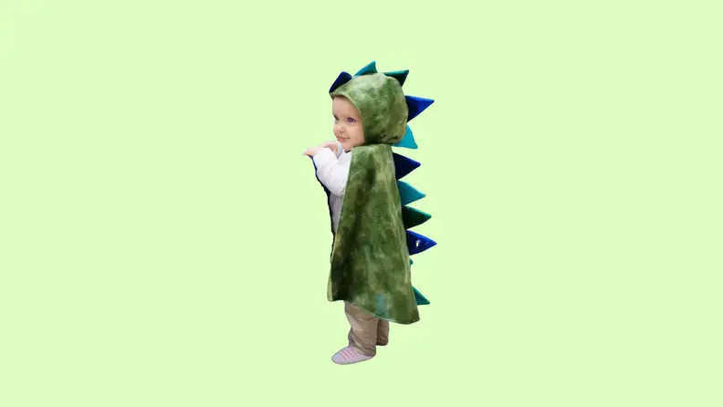 A toddler wearing a green dragon costume.