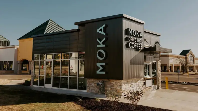Moka drive thru coffee building with black paneling and stone base
