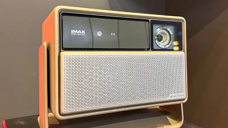An XGIMI Horizon 20 series projector is displayed on a stand under bright lighting. The front panel shows the IMAX Enhanced logo alongside the lens, with a silver perforated speaker grille.