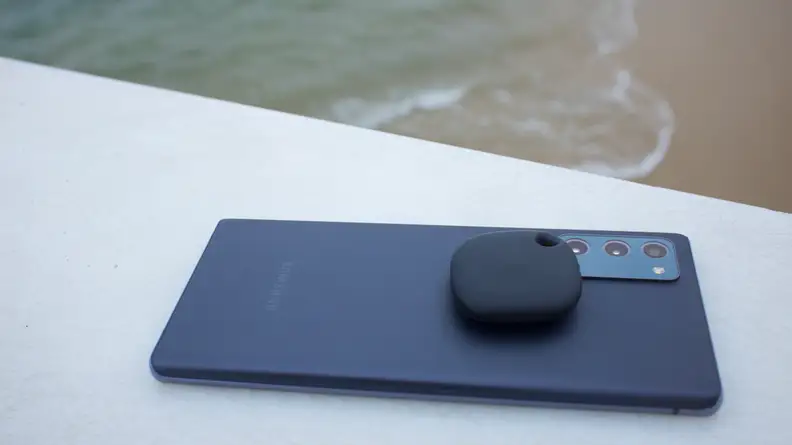 A Samsung Galaxy Smart Tag sitting atop a Samsung Galaxy S21 Ultra.