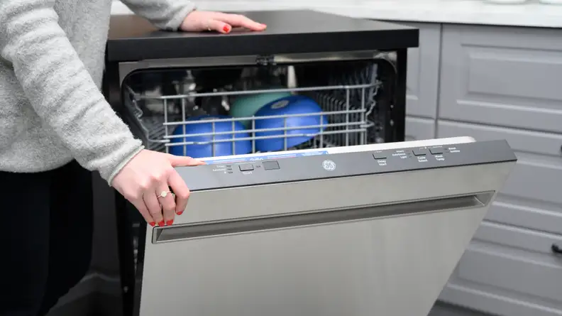 The door of the The GE GPT225SSLSS portable dishwasher is slightly ajar, revealing its control panel's array of buttons.