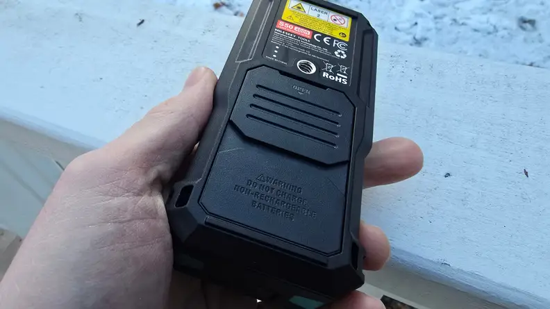 A hand holds a laser level