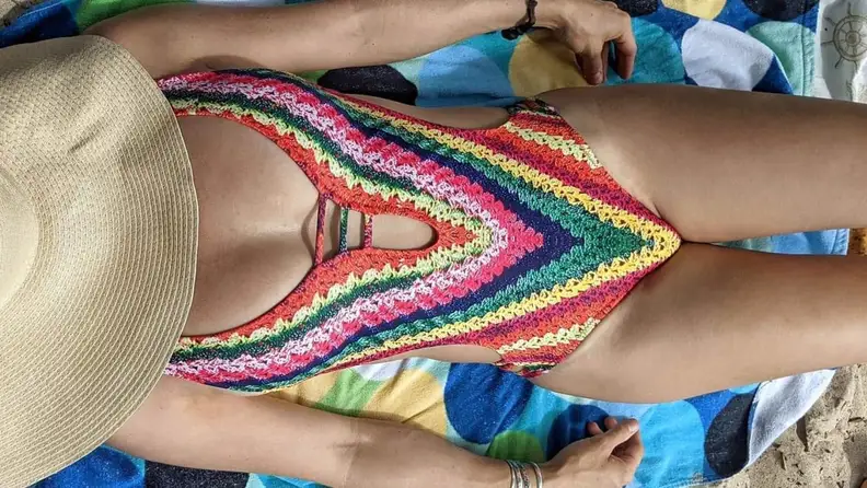 A cropped photo of a woman's torso lying on a beach