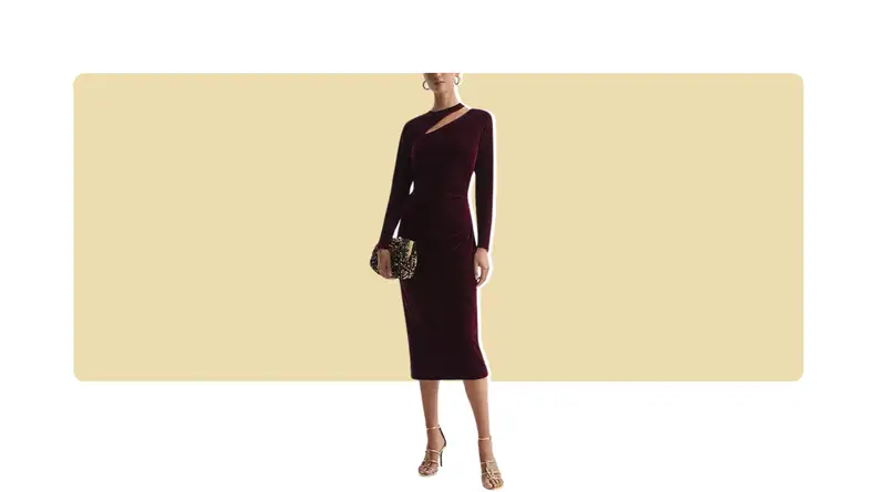 A model wearing a form-fitting red velvet dress with a cutout detail along the neckline. She holds a purse.