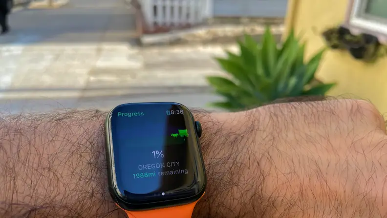 A person holds out their wrist to monitor how far they've walked on the Apple Watch's Oregon Trail app.