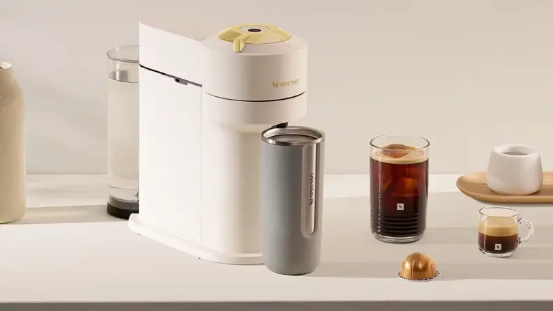 White Nespresso machine with a travel tumbler, iced coffee and an espresso