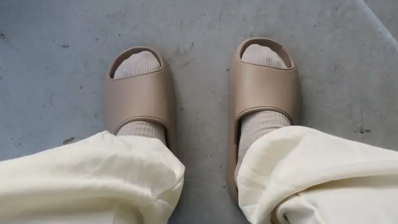 Pair of feet standing in Litfun pool slides in color beige.