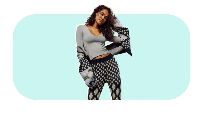 Model showcasing a heather gray Free People Clean Lines Voop Long Sleeve shirt with printed leggings.