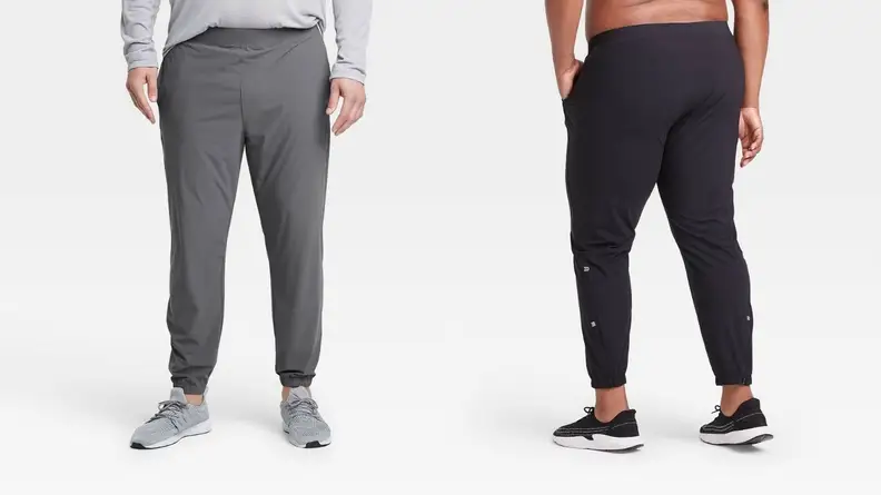 A pair of models pose in two styles of jogging pants (one gray and one black).