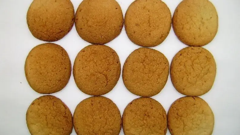 Three rows of sugar cookies with uneven baking—darker in the middle and lighter on the edges