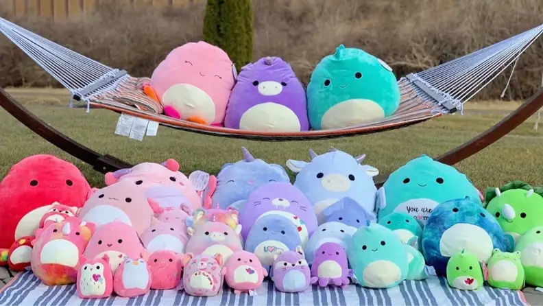 Squishmallows sitting on top of a hammock and on the ground in front of it
