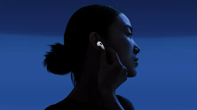 Woman wearing AirPods 5 in a dark silhouette image against a blue background.